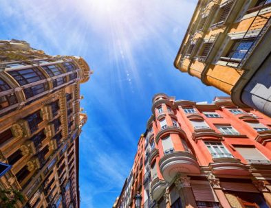 Madrid Spain. Antique Spanish architecture of old buildings at crossroad among grand metropolis houses on the background of blue sky with sunshine rays. Summer day.